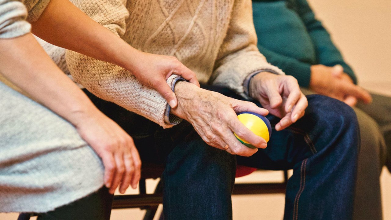 Zorgmedewerker helpt een oudere patiënt met een bewegingsoefening.