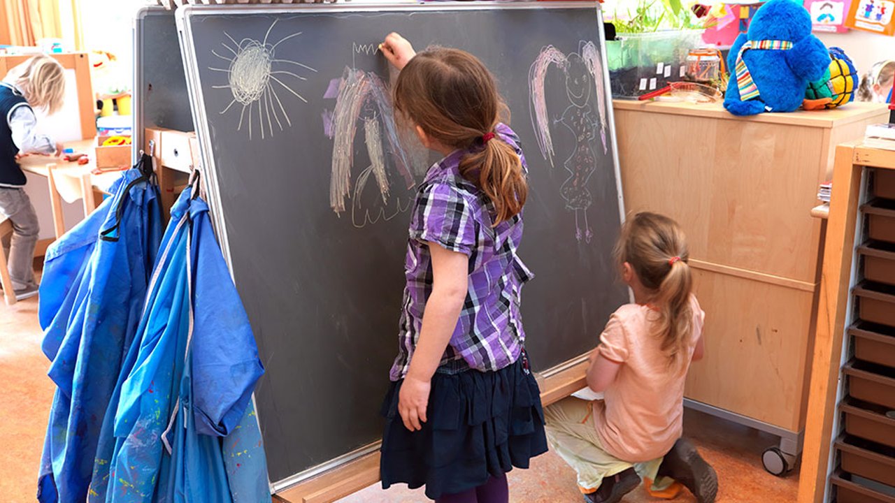 Meisjes krijten op een schoolbord.