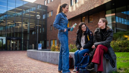 Een groep studenten zit en staat voor Hogeschool Leiden en praten geamuseerd