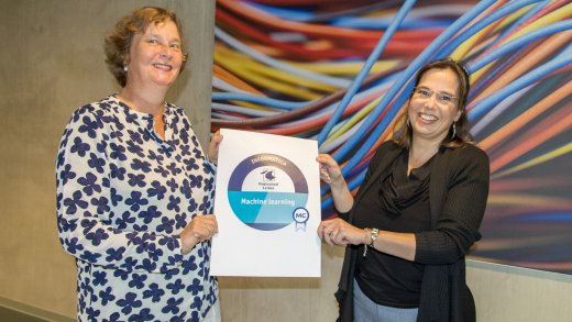 Foto van twee docenten die het logo voor het microcredential machine learning laten zien