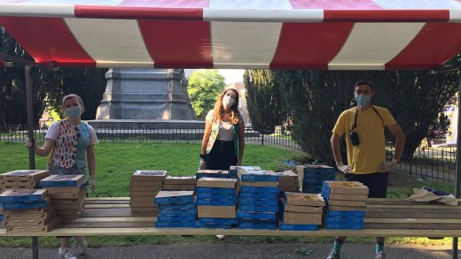 Meerdere organisatoren met een tafel vol pizzas