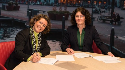 Twee vrouwen rond een tafel ondertekenen wat papieren