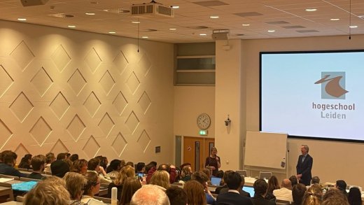 Robbert Dijkgraaf samen met Tweede Kamerlid Jeanet van der Laan in gesprek met studenten in de collegezaal