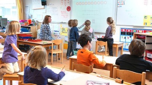 Overzichtfoto van een klas vol met kinderen. De foto is van achteren geschoten.