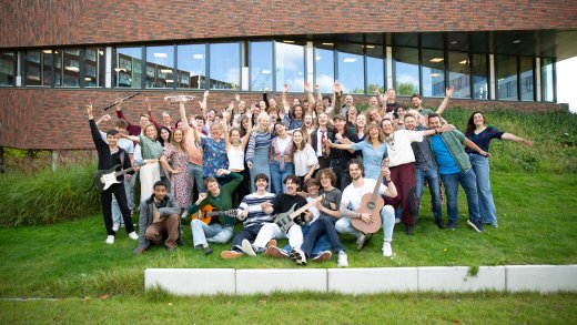 Alle docenten van de opleiding Docent Muziek poseren voor een groepsfoto voor het gebouw van Hogeschool Leiden
