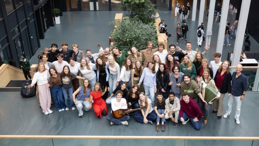 Alle docenten van de opleiding Docent Muziek poseren voor een groepsfoto in het atrium van Hogeschool Leiden