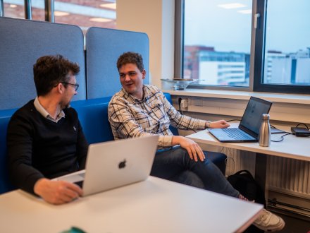 Lector en student LCAB hebben bespreking op banken met laptop