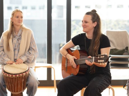 Studenten bespelen een djembe en een gitaar 