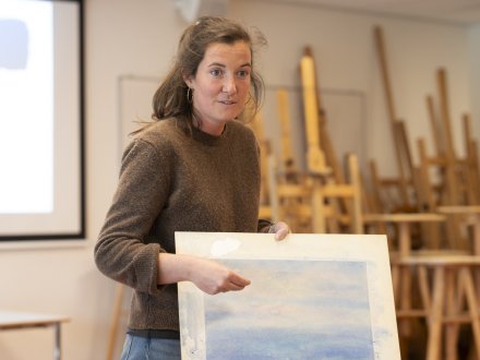 Docent geeft uitleg aan de hand van een schilderwerk