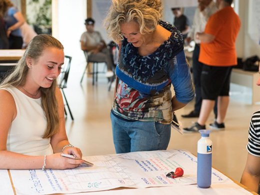 Een student laat iets op haar telefoon zien aan een docent.