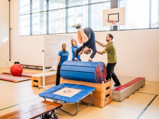 Docent IP Pabo sportklas tijdens les maken helpen studenten elkaar salto maken 