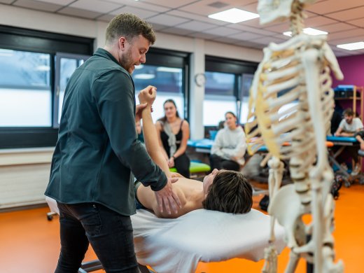 Fysiotherapie les waarin docent praktijkoefeningen laat zien 