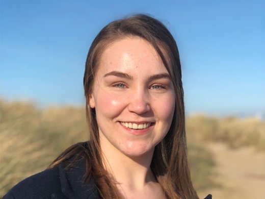 Foto van Gaya (student Chemie) met duinen op het achtergrond