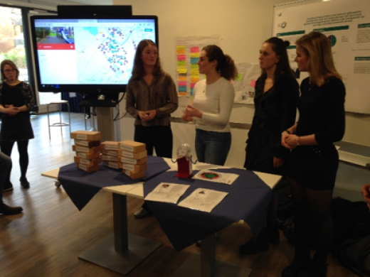 Vier personen staan bij een tafel met erachter een digibord