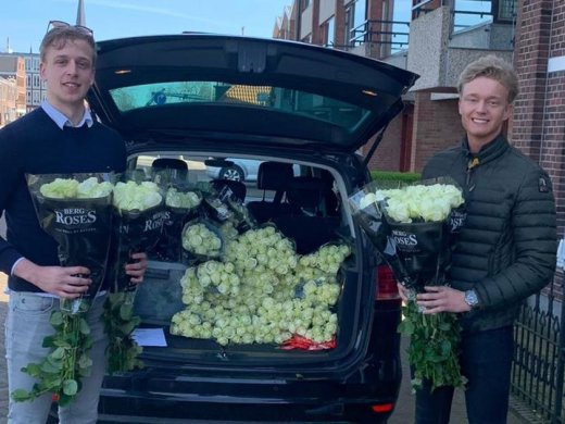 Foto van Harry en Jelle bij de achterbak van een auto die vol ligt met bloemboeketten. Ze hebben zelf ook bloemboeketten vast.