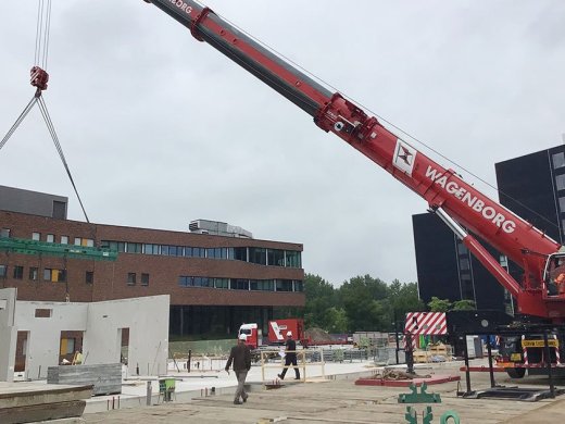 Een foto van de bouwplaats voor de hogeschool, inclusief hijskraan