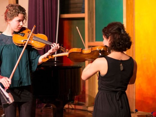 Een docent muziek geeft instructies aan een andere student over de viool