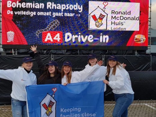 Foto van vijf mensen die voor een groot doek staan waarop staar "A4 Drive-in" en "Bohemian Rhapsody, De volledige omzet gaat naar -> Ronald McDonald Huis Leiden". Ook hebben ze een doek vast waar het logo van Ronald McDonald opstaat met de tekst "Keeping families close".