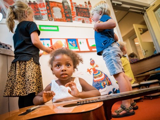 Vakspecialist muziek kind speelt met gitaar in de klas