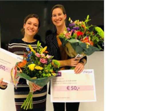 Twee personen staan naast elkaar met twee 50 euro cheques en twee bloemboeketten