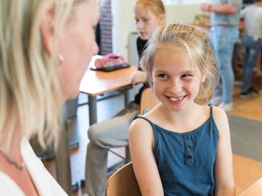 Kindje lacht naar juf in klas
