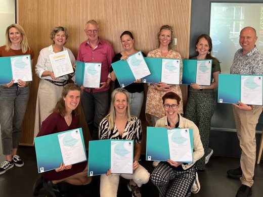 Lector Christiane Nieuwmeijer met negen cursisten die het certificaat Train de Trainer Muzikaal Spel hebben behaald en trots tonen.