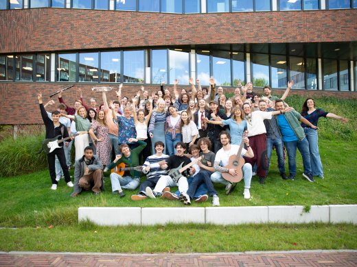 Alle docenten van de opleiding Docent Muziek poseren voor een groepsfoto voor het gebouw van Hogeschool Leiden