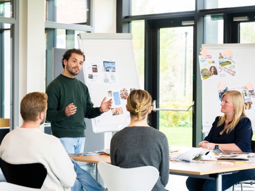 Een persoon geeft les voor een klas met studenten.