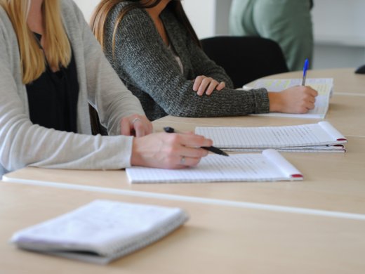 Studenten zitten aan een tafel en maken notities
