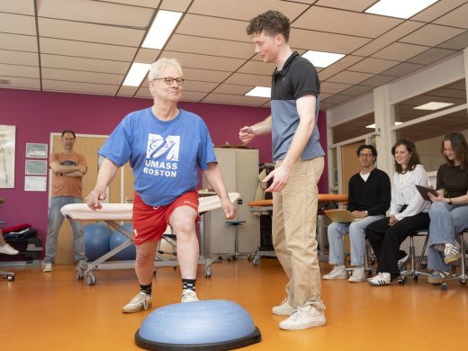 Een student Fysiotherapie begeleidt een simulant.
