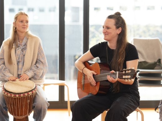 Studenten bespelen een djembe en een gitaar 
