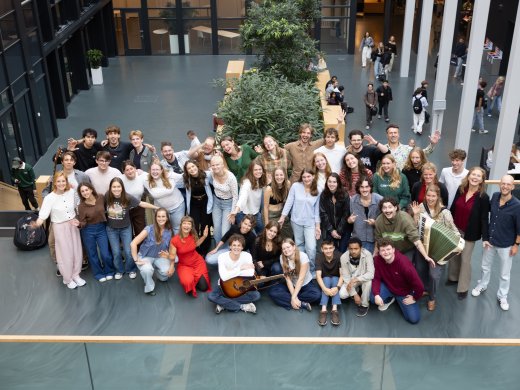 Alle docenten van de opleiding Docent Muziek poseren voor een groepsfoto in het atrium van Hogeschool Leiden