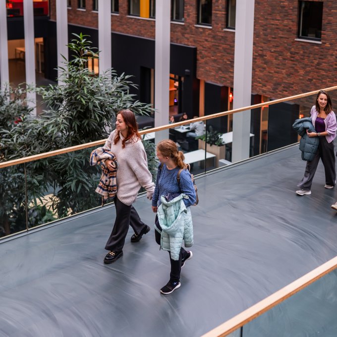Studenten lopen op een centraal punt in Hogeschool Leiden die de sfeer van de school geeft