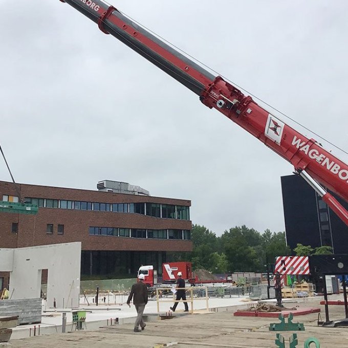 Een foto van de bouwplaats voor de hogeschool, inclusief hijskraan