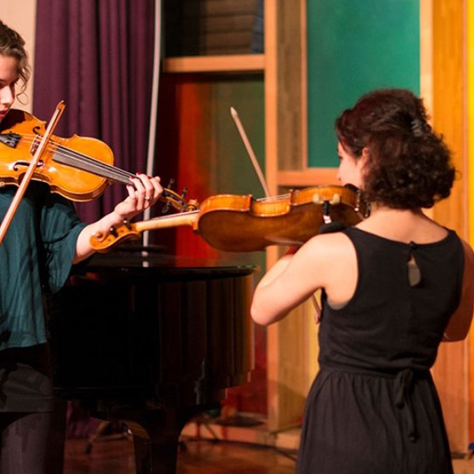 Een docent muziek geeft instructies aan een andere student over de viool