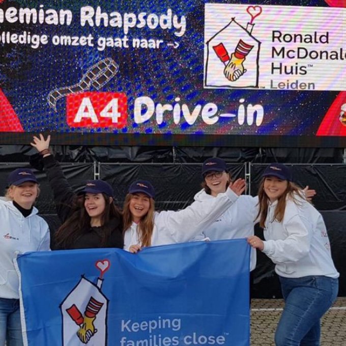 Foto van vijf mensen die voor een groot doek staan waarop staar "A4 Drive-in" en "Bohemian Rhapsody, De volledige omzet gaat naar -> Ronald McDonald Huis Leiden". Ook hebben ze een doek vast waar het logo van Ronald McDonald opstaat met de tekst "Keeping families close".