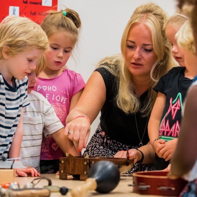 Muziekdocent geeft uitleg aan kleutergroep