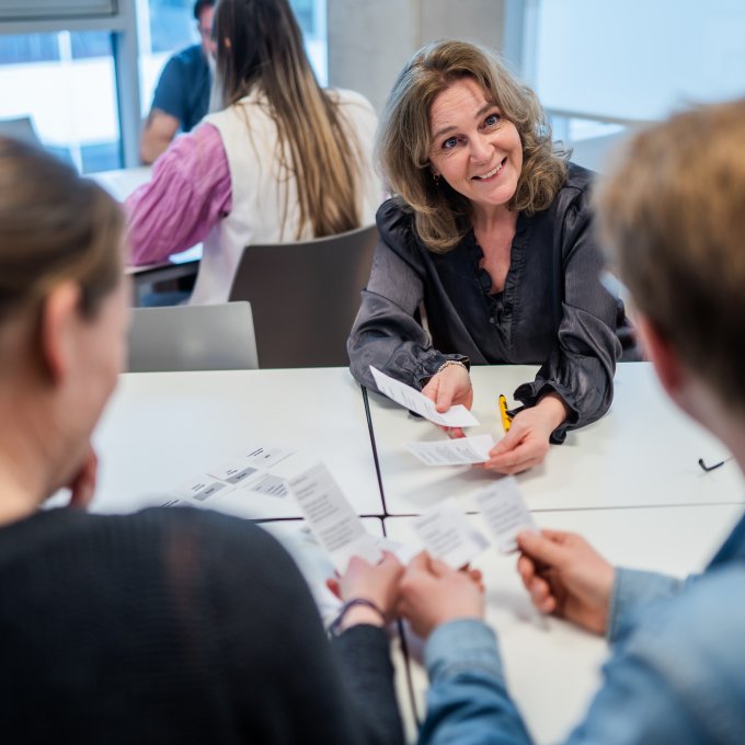 Docent en studenten HRM doen een interactief kaartspel in de klas
