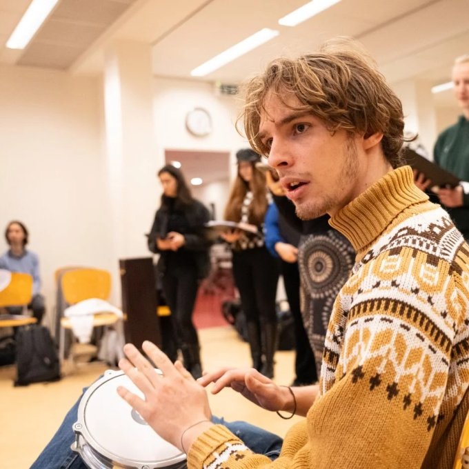 Focusbeeld op jongen op trommel met veel verschillende muzikanten om zich heen