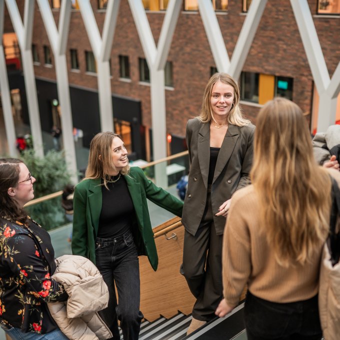 Groepje studenten pratend op trap in hoofdgebouw Hogeschool Leiden