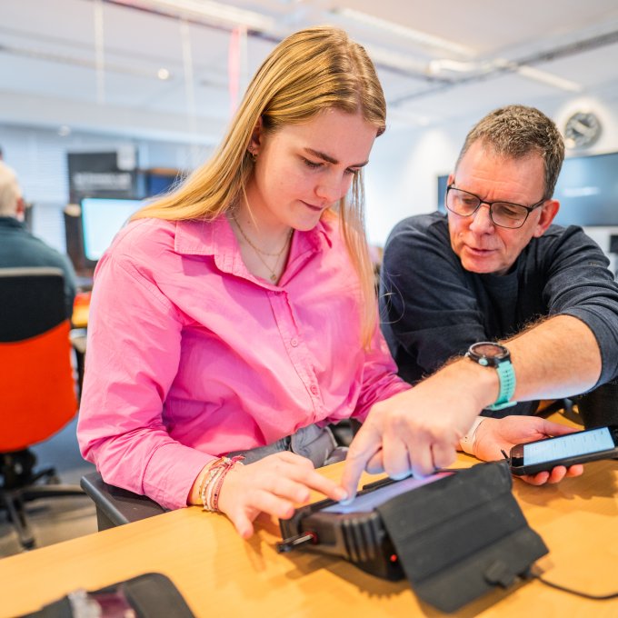 Docent geeft uitleg aan student Forensisch ICT over het uitlezen van een mobiele telefoon in het Digital Forensics Lab op de HSD-Campus