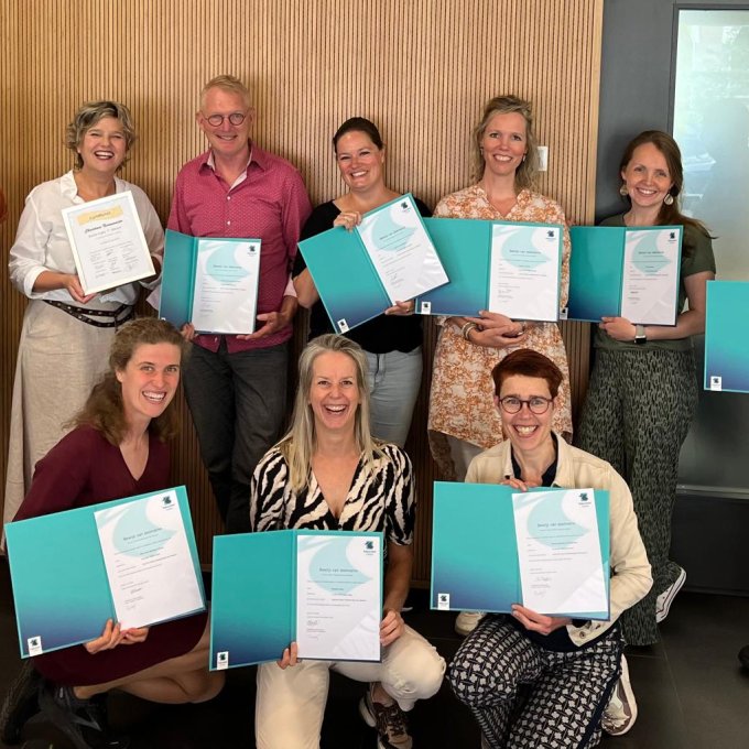 Lector Christiane Nieuwmeijer met negen cursisten die het certificaat Train de Trainer Muzikaal Spel hebben behaald en trots tonen.