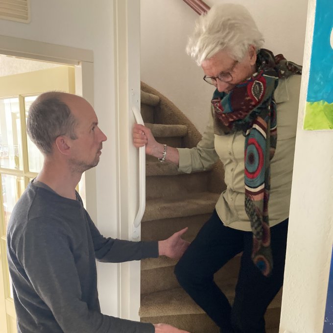 Behandelaar met ouder persoon die de trap afloopt