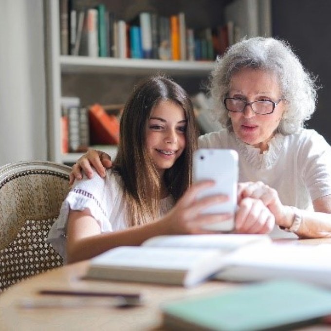 Meisje en oudere dame kijken samen op telefoon