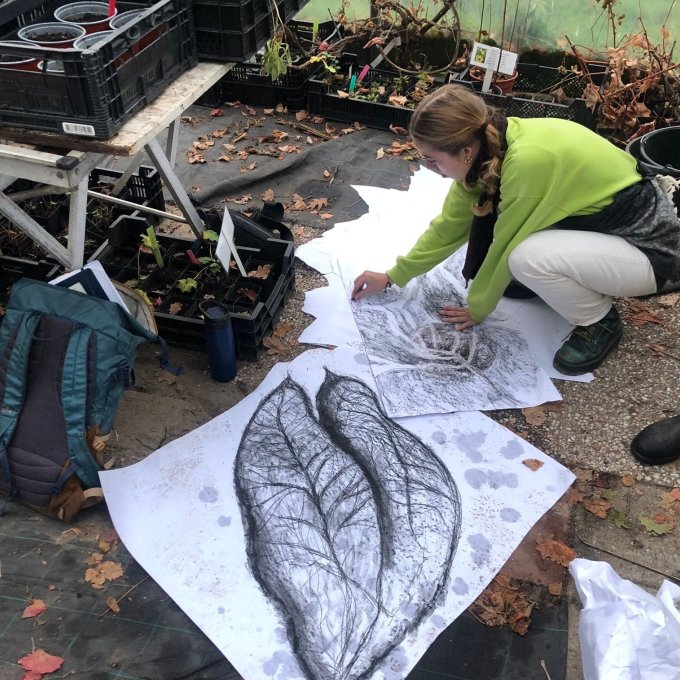 Studenten in tuin tekenen bladeren op grote vellen papier