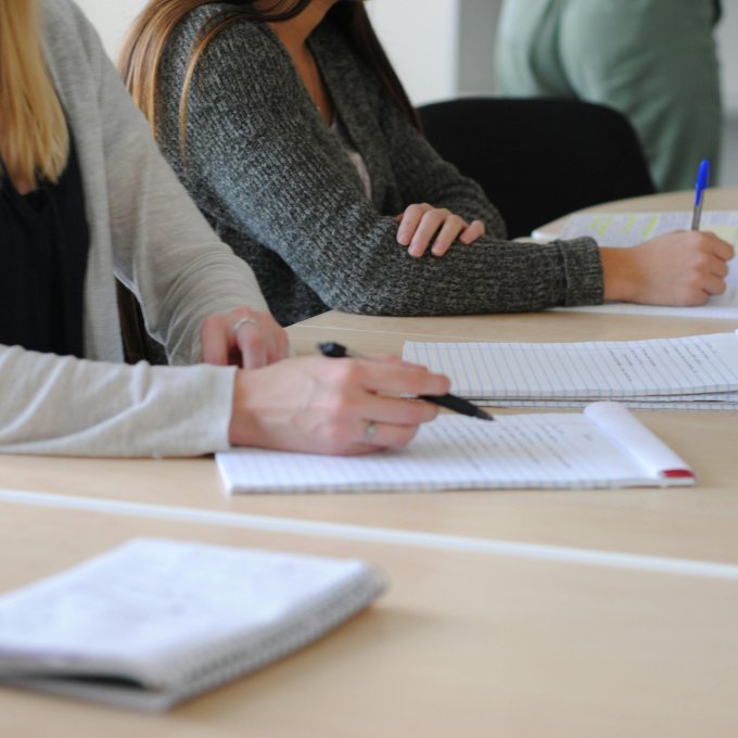 Studenten zitten aan een tafel en maken notities