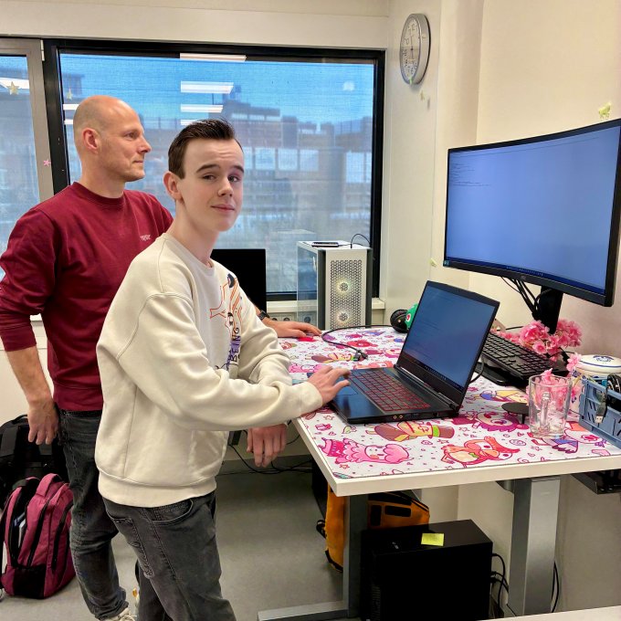 Tom staat samen met Koen aan het bureau