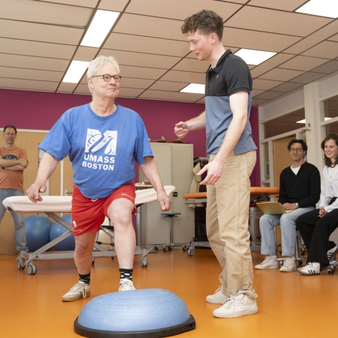 Een student Fysiotherapie begeleidt een simulant.