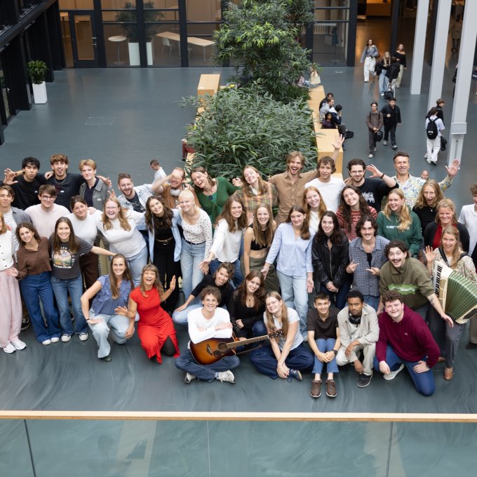 Alle docenten van de opleiding Docent Muziek poseren voor een groepsfoto in het atrium van Hogeschool Leiden